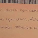 Rokrakstā rakstīts teksts par barikāžu simbolu ugunskuru.