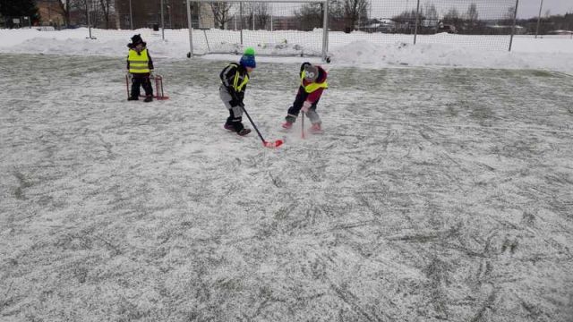 bērni spēlē florbolu