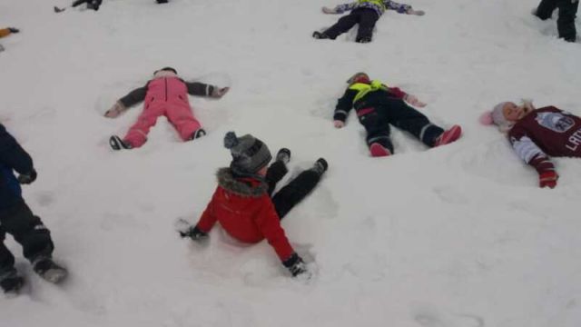 bērni sniegā zīmē sniega ēņģeļus